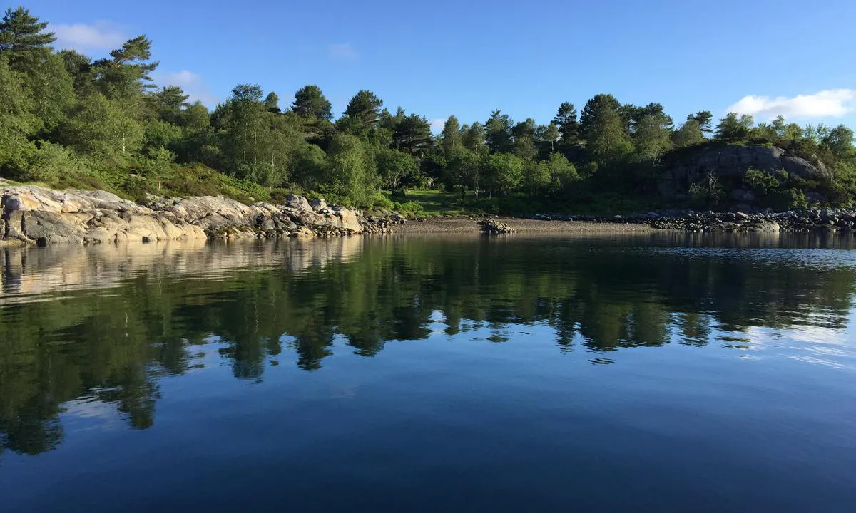 Ådnøya: Grusstrand og gressbakke, fortøyning mot fjellet.