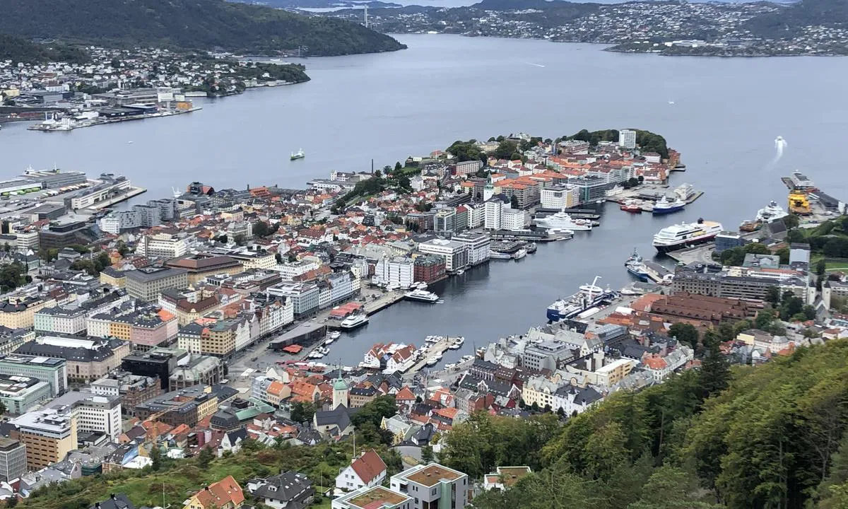 Utsikt fra Fløyen over Bergen og Bergen Gjestehavn. Gjestehavna ligger innerst i vågen i senter av bildet. Du ankommer nordfra og det er mye kommersiell trafikk på vei inn til gjestebryggene.