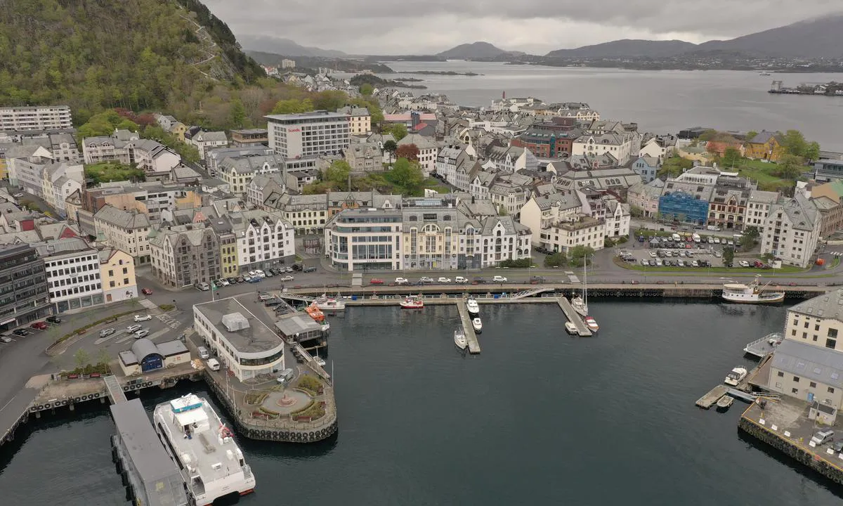 Oversiktsbilde av Ålesund Havn, tatt fra den vinkelen du kommer seilende inn i havna. Gjestebrygga er de tre flytebryggene du ser rett frem. Vær oppmerksom på hurtigbåtene som har hyppige anløp til venstre i bildet.