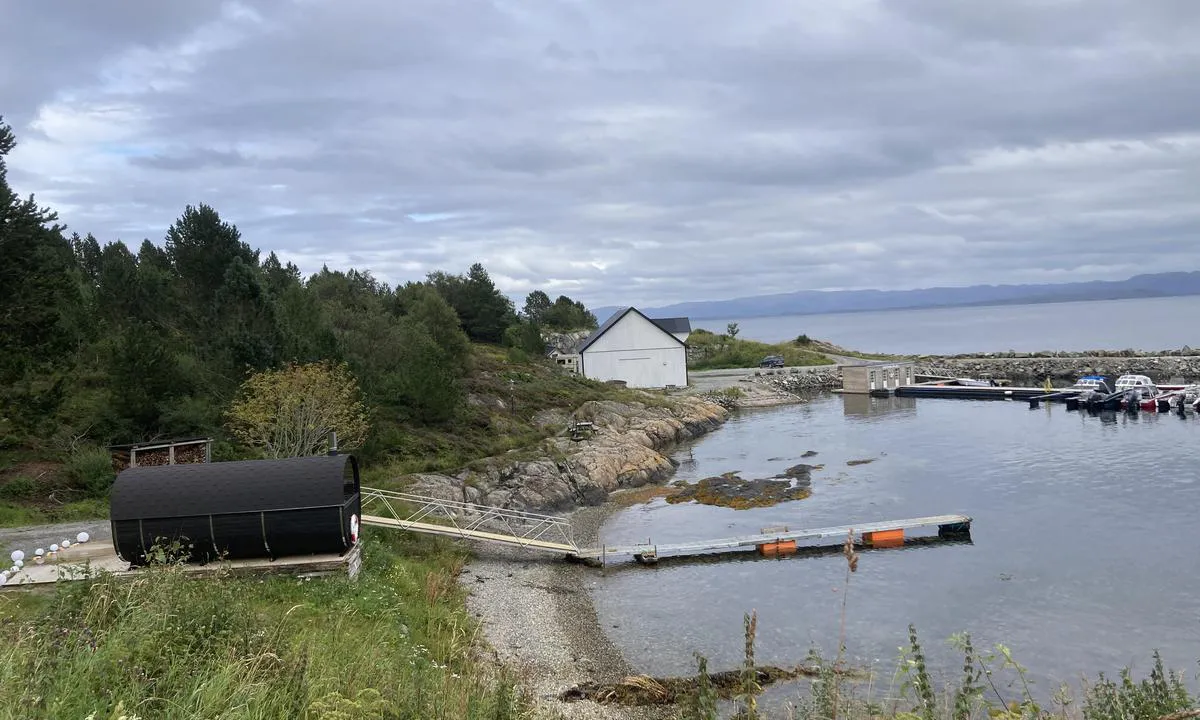 Fjellvær: Bilde tatt fra parkering for bobil. I forgrunn vises sauna med badebrygge. Bak sauna står en badestamp fylt med sjøvann.