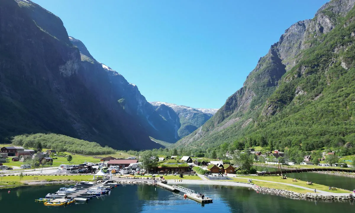 Gudvangen, Nærøyfjord: {"base": "no", "no": "Gjestebrygge midt i bildet, bensinstasjon/joker butikk.  Vikinglandsby, kajakkutleige og badestrand", "se": "G\u00e4stbrygga mitt i bilden, bensinstation/joker-butik. Vikingaby, kajakuthyrning och badstrand", "en": "Guest pier in the middle of the picture, gas station/Joker store. Viking village, kayak rental, and bathing beach", "da": "G\u00e6stebro midt i billedet, benzinstation/joker butik. Vikingelandsby, kajakudlejning og badestrand"}