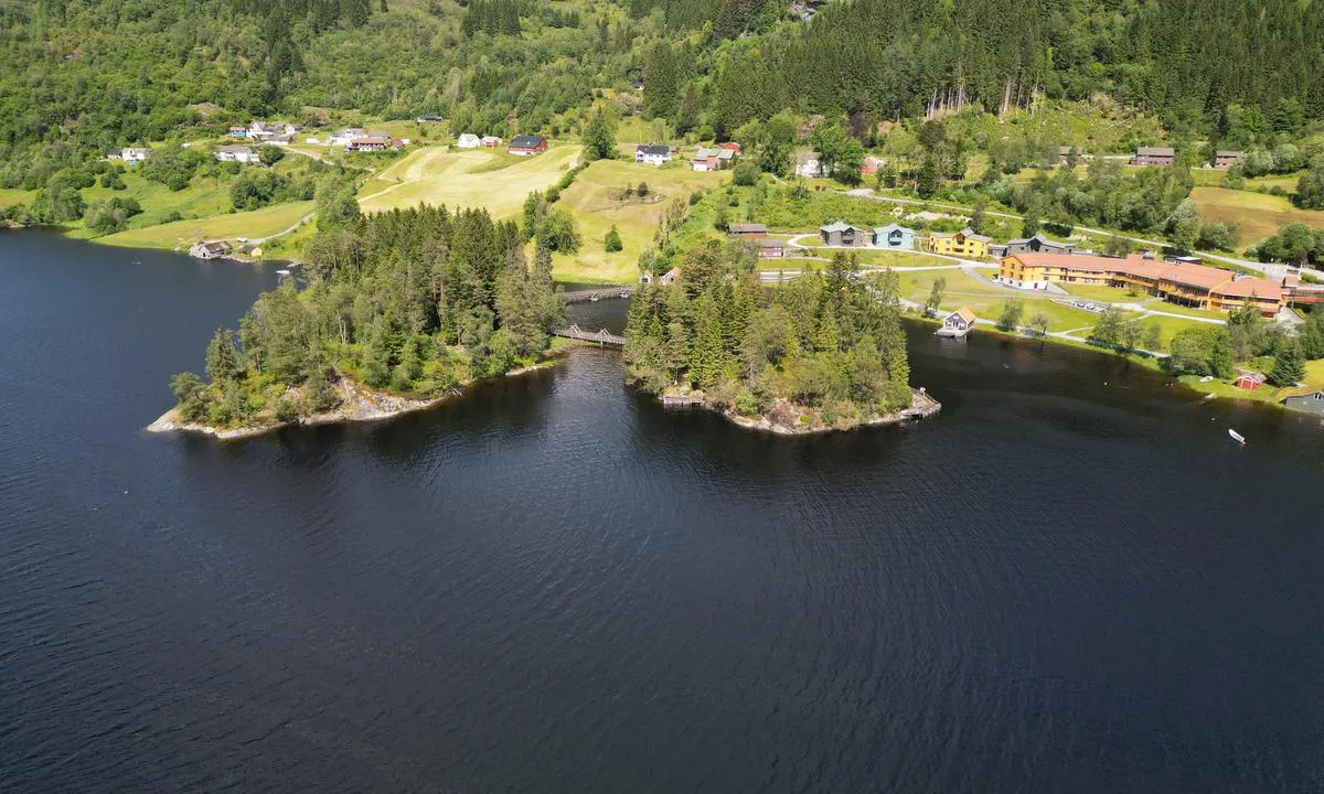 Haugland: {"base": "no", "no": "Trekai p\u00e5 holmen til h\u00f8gre.  Holmane har gangbruer mellom seg og inn til \"fastlandet\"", "se": "Tr\u00e4brygga p\u00e5 holmen till h\u00f6ger. Holmarna har g\u00e5ngbroar mellan sig och in till \"fastlandet\"", "en": "Wooden piers on the islet to the right. The islets have footbridges connecting them to each other and to the mainland.", "da": "Tr\u00e6kaj p\u00e5 holmen til h\u00f8jre. Holmerne har gangbroer mellem sig og ind til \"fastlandet\""}