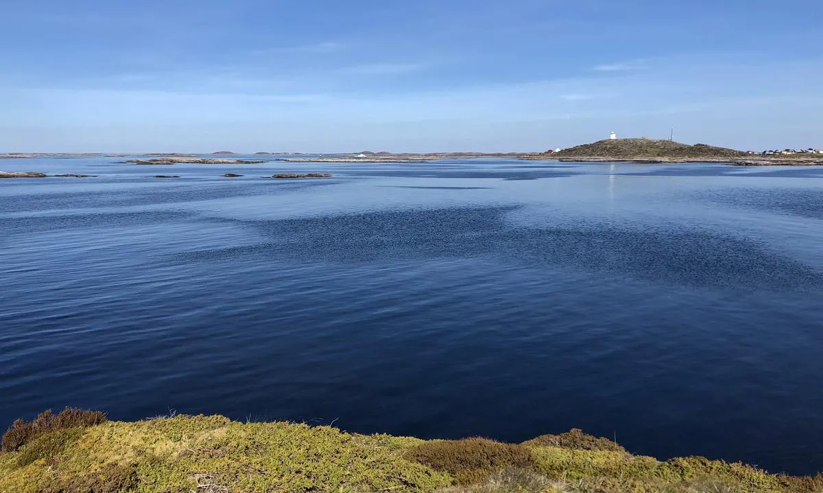 Utsikt fra Kallholmen og ned på ankringsplassen. Bildet er tatt mot øst, og bakgrunnen ser du det karakteristiske fyret på Sula. Du ser den hvite fyrbygningen på toppen av berget i lang tid før du kommer inn mot Sula.