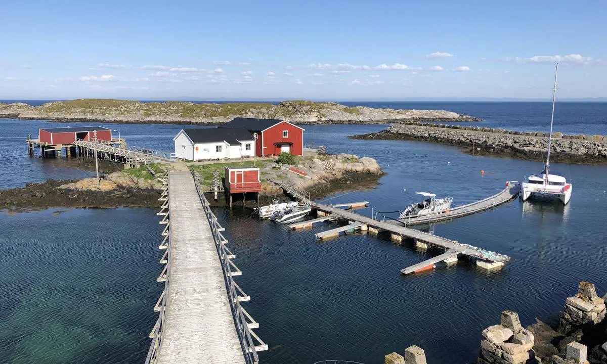 Gjestebrygga på Sauøya er den avrundede flytebrygga til høyre i bildet. I det røde huset er det WC og dusj. Bildet er tatt mot øst.