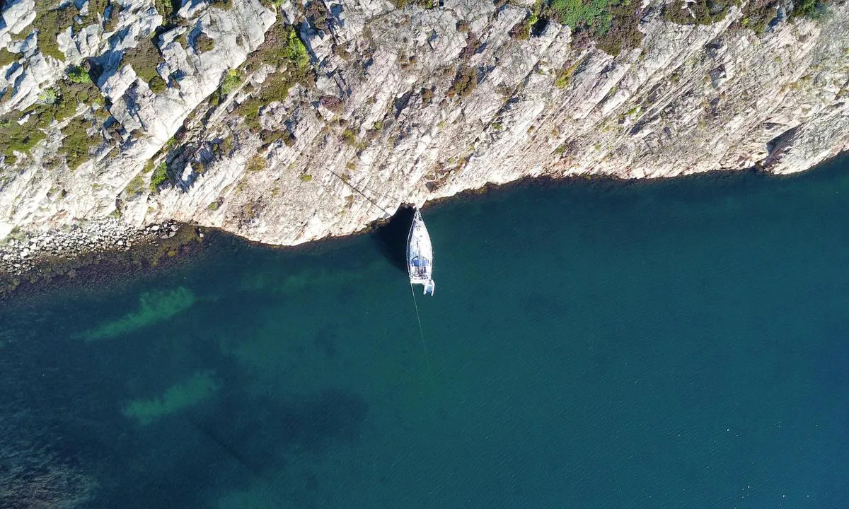 Sailboat moored bow-to towards the rocks on the north side of Sladholmen