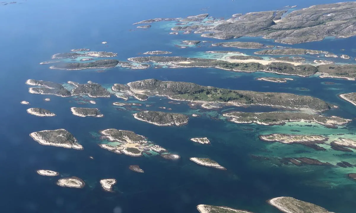 Torghatten - Flagøya: Flyfoto tatt fra nordøst. Den oppmerkede ankringsplassen er lengst til venstre i bildet, og som vi ser er det fin sandbunn langt innover/nordover, så også mulig å trekke lenger inn mellom øyene.